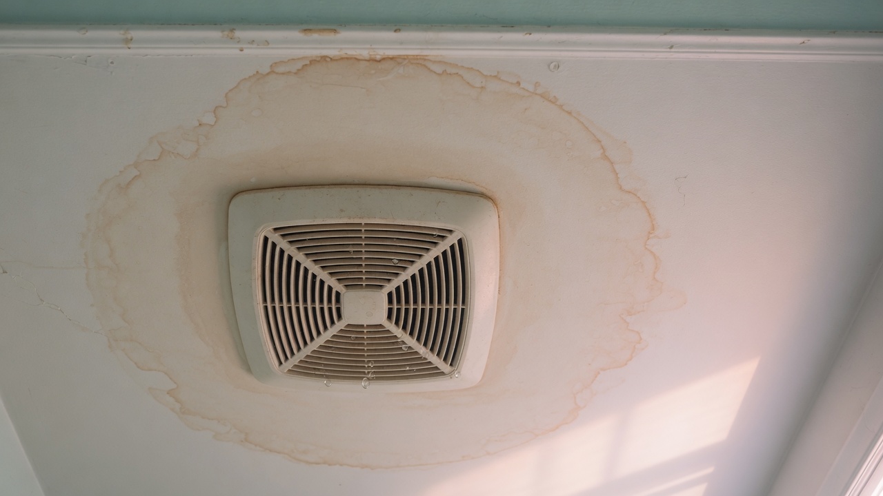 Water droplets on a bathroom ceiling exhaust fan grille in a San Diego home